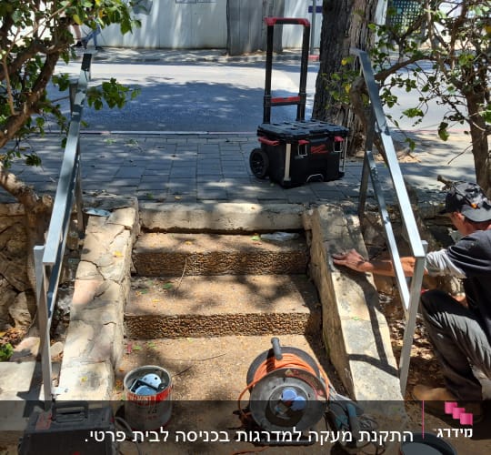 מעקה מתכת מותקן על מדרגות אבן בגן ציבורי